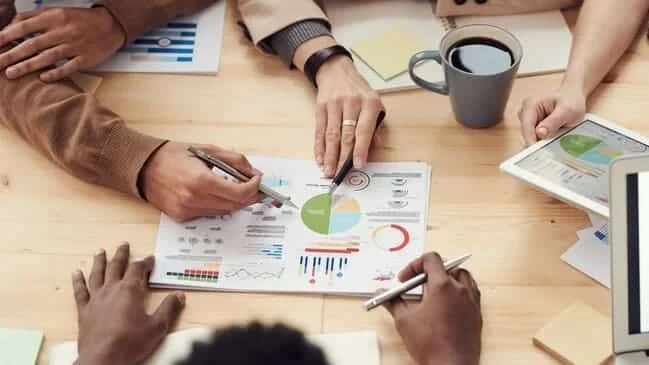 Equipa a analisar relatórios e gráficos em redor de uma mesa
